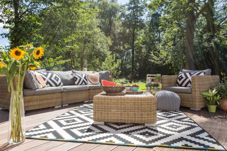Patio seating area with a black and white statement rug and matching pillows.
